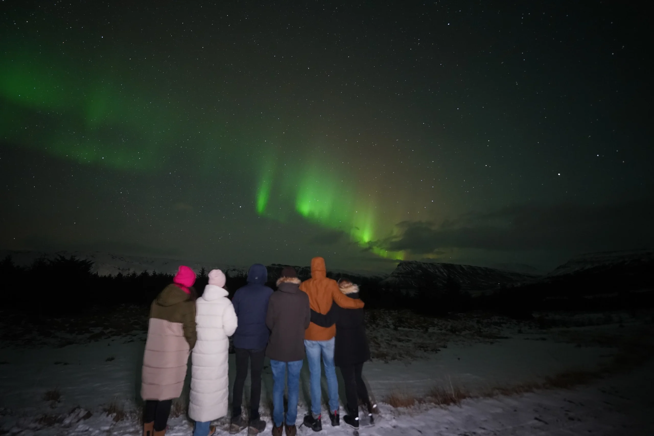 Groep kijkt naar het Noorderlicht tijdens een personeelsuitje in IJsland